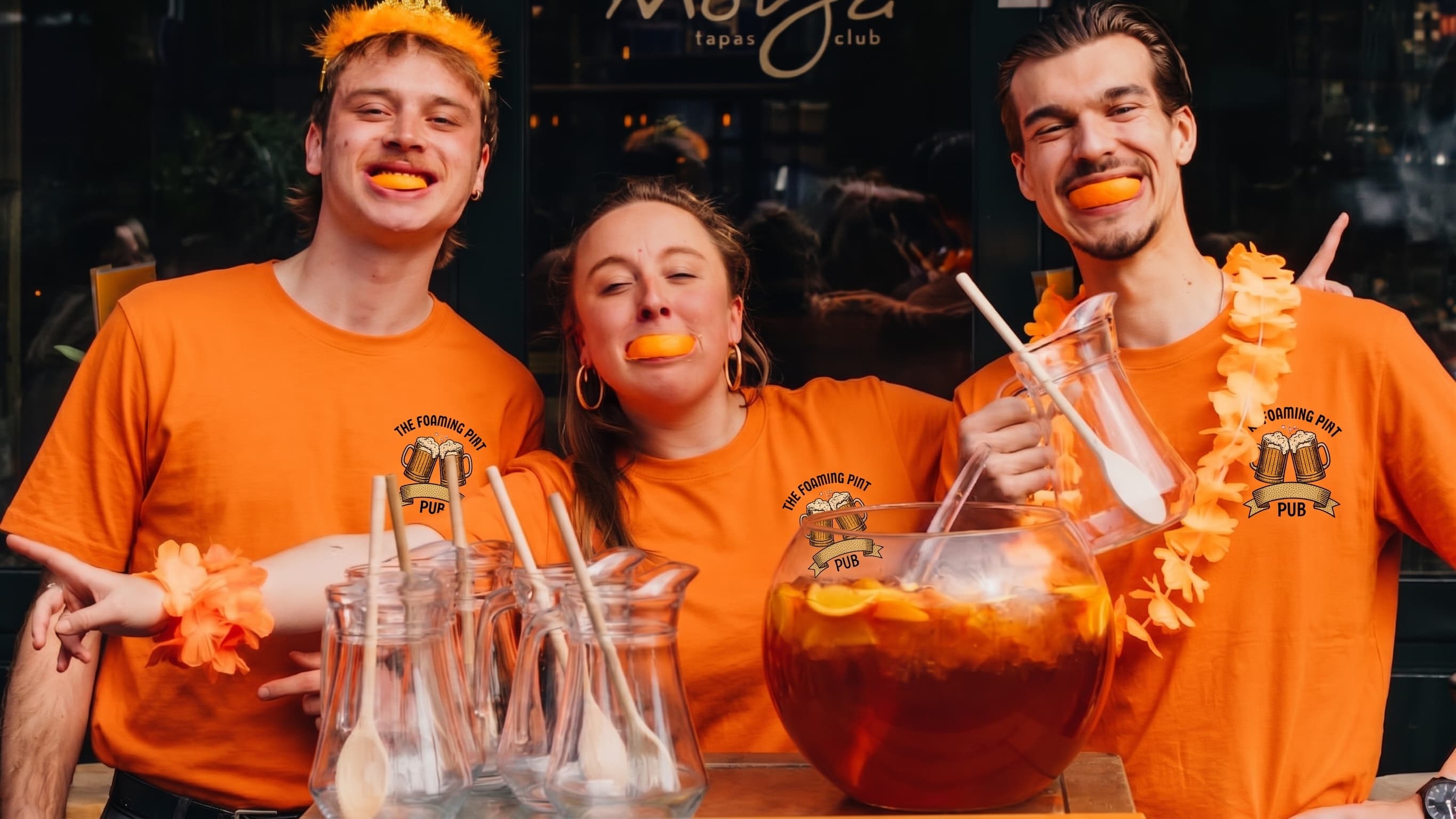 Crew in oranje shirts met eigen logo, samen aan de bar